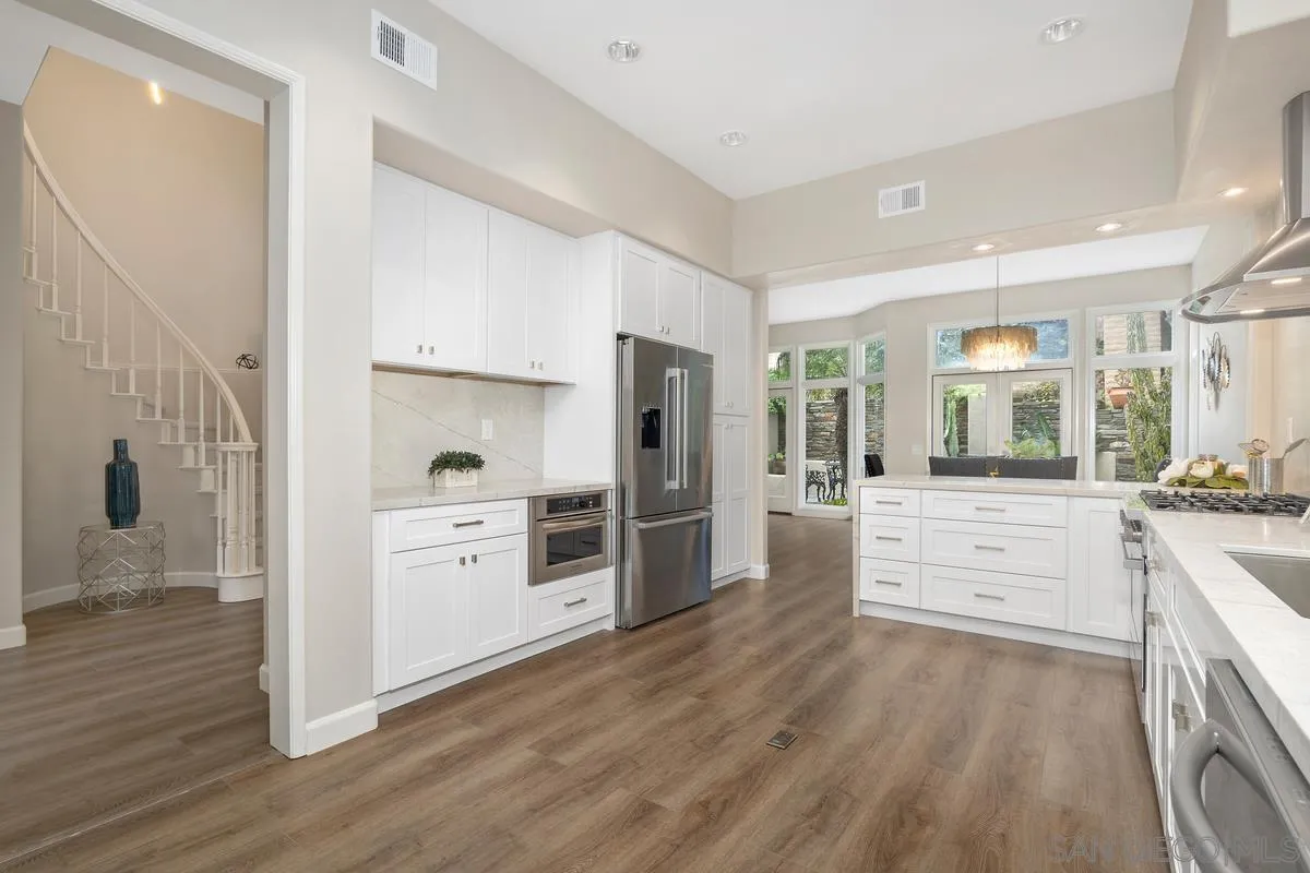9605 Claiborne Square La Jolla, CA 92037 - Photo 20 of 34 a kitchen with white cabinets and stainless steel appliances