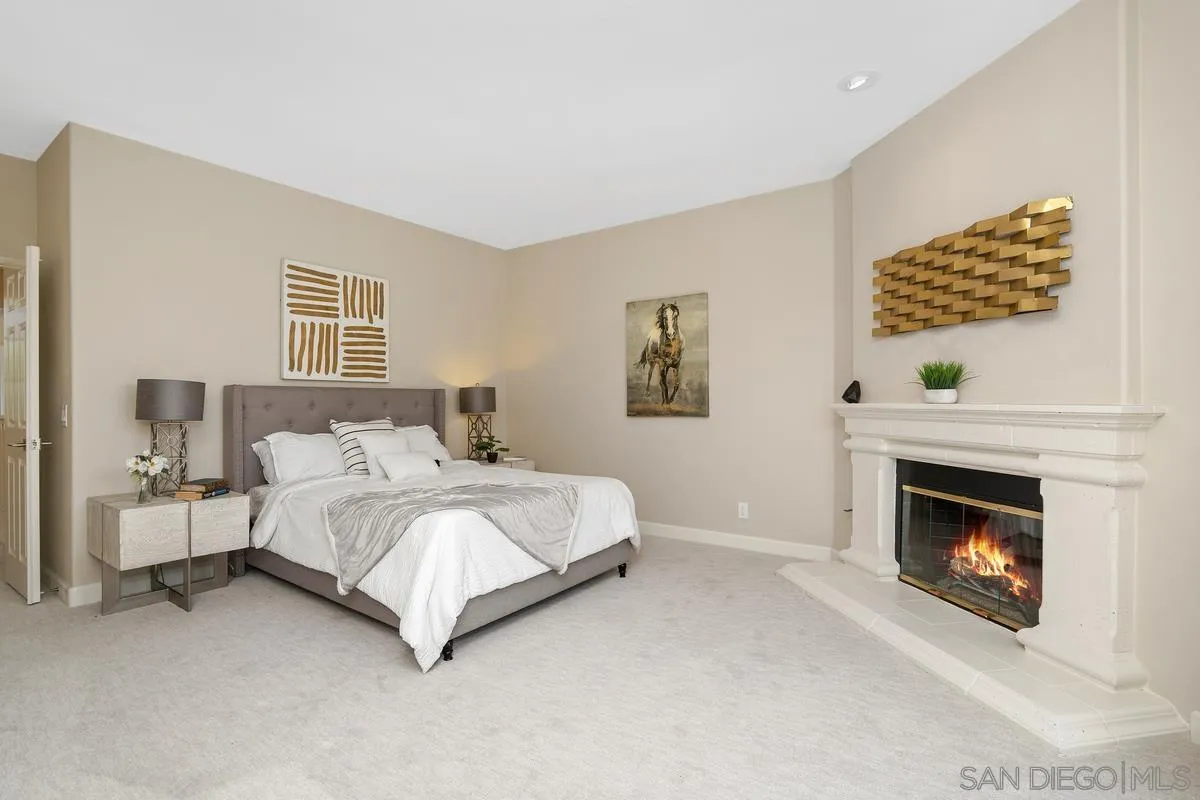 9605 Claiborne Square La Jolla, CA 92037 - Photo 22 of 34 a spacious bedroom with a bed and a fireplace