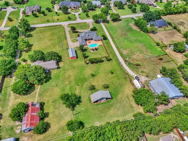 an aerial view of a residential houses with outdoor space and trees