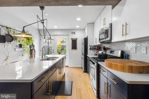 a large kitchen with stainless steel appliances granite countertop a sink a stove and a refrigerator