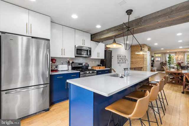 a kitchen with kitchen island a refrigerator a stove a microwave oven a sink with island and chairs