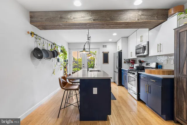 a kitchen with stainless steel appliances granite countertop a stove a refrigerator a sink and a dining table with wooden floor