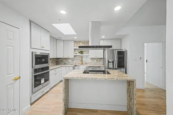 a kitchen with kitchen island stainless steel appliances granite countertop a stove and a refrigerator