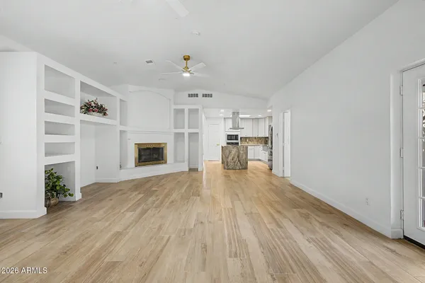 a view of empty room with wooden floor and a window