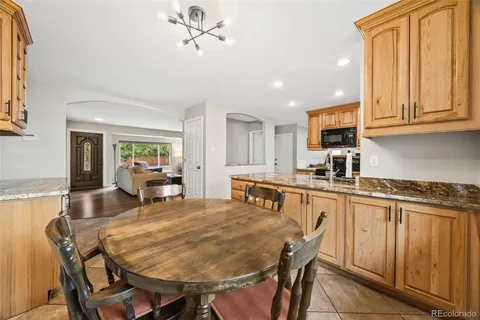 a kitchen with stainless steel appliances granite countertop table chairs sink and cabinets