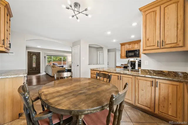 a kitchen with stainless steel appliances granite countertop table chairs sink and cabinets