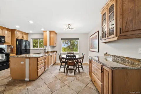 a kitchen with stainless steel appliances granite countertop a stove top oven a sink a dining table and chairs with wooden floor