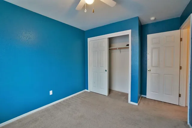 an empty room with closet and a chandelier fan