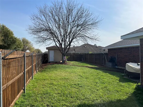 a backyard of a house with wooden fence and large trees