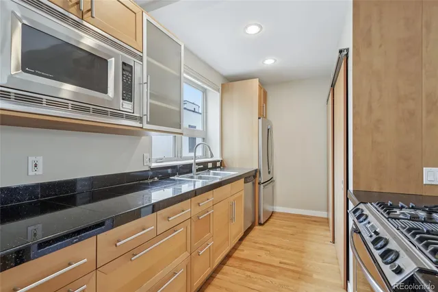 a kitchen with granite countertop a sink stove and refrigerator