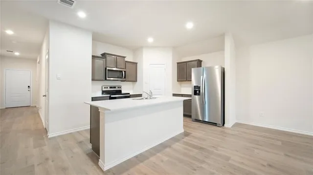 a view of kitchen with granite countertop stainless steel appliances refrigerator and microwave