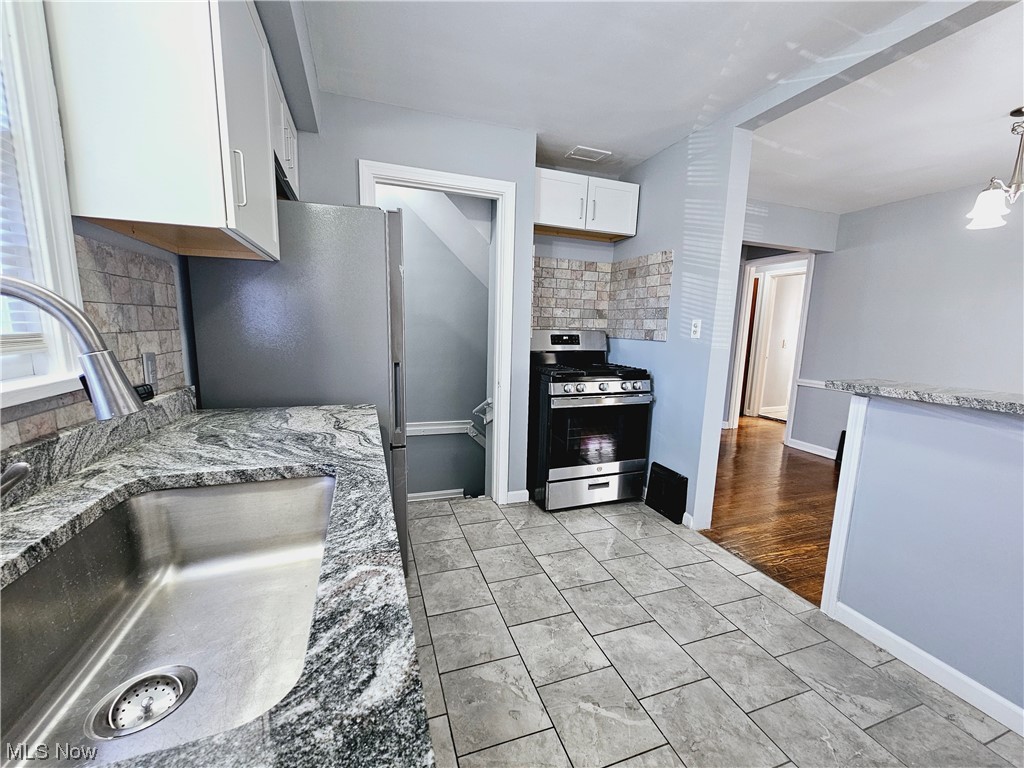 884 Yellowstone Road Cleveland Heights, OH 44121 - Photo 3 of 17 Kitchen with stainless steel range with gas cooktop, white cabinetry, decorative light fixtures, backsplash, and sink