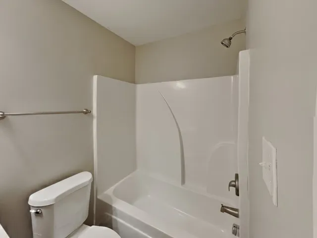 a white toilet sitting next to a bath tub