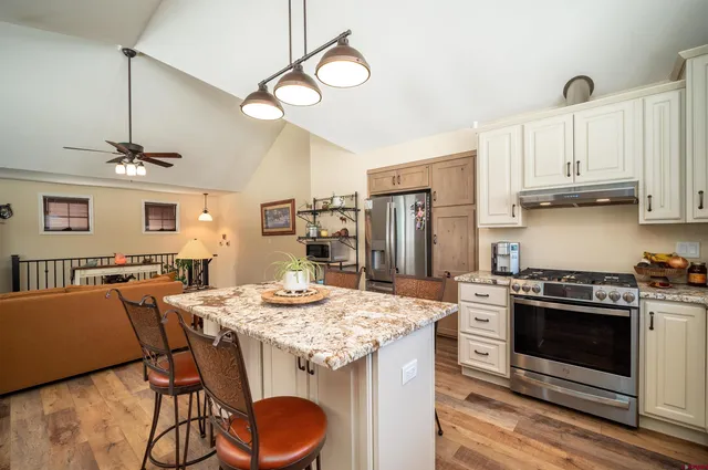 a kitchen with stainless steel appliances kitchen island a table chairs in it and wooden floors