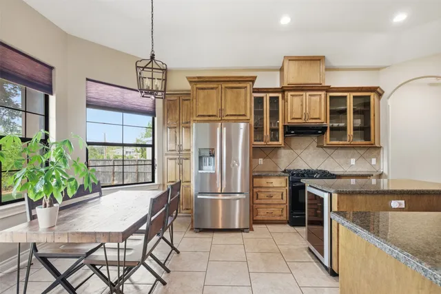 a kitchen with stainless steel appliances granite countertop a refrigerator a microwave a dining table and chairs with wooden floor