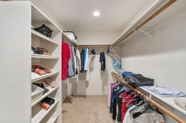 a view of walk in closet with clothes and shoes