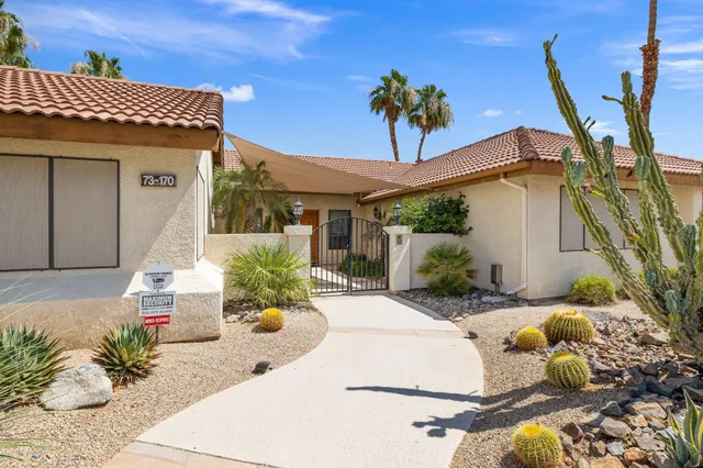 a view of a white house with a potted plant and a table