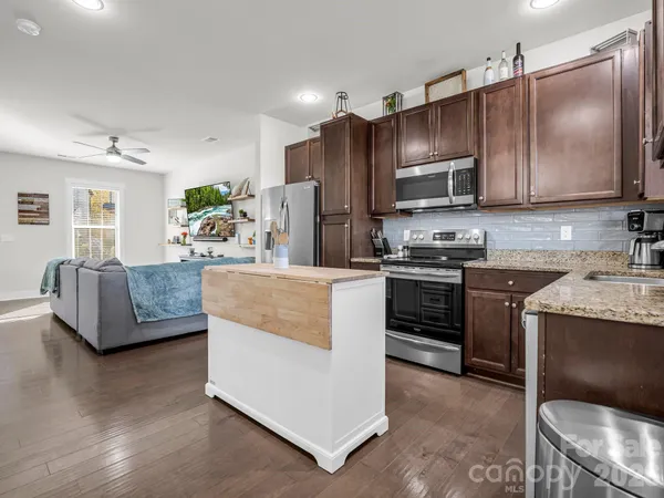a kitchen with kitchen island granite countertop a sink a stove oven a counter top space and cabinets