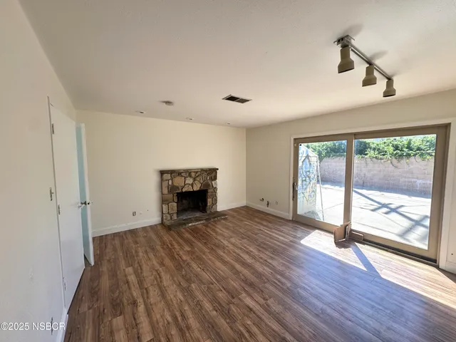 a view of empty room with wooden floor and fireplace
