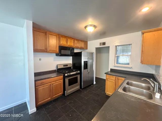 a kitchen with granite countertop a sink stainless steel appliances and cabinets