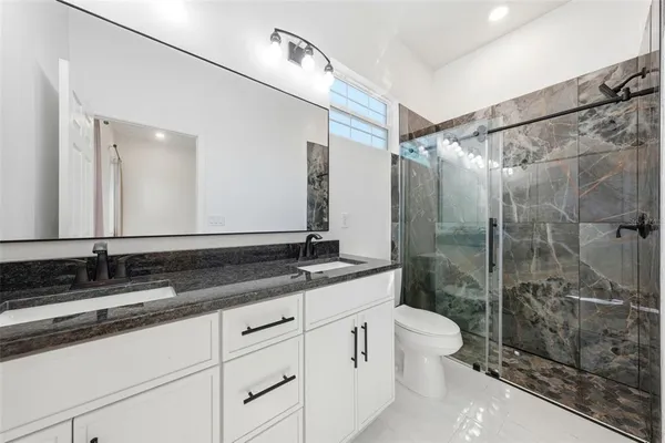 a bathroom with a double vanity sink toilet mirror and shower