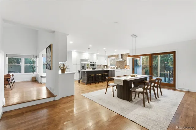 a dining hall with stainless steel appliances kitchen island granite countertop a dining table and chairs with wooden floor