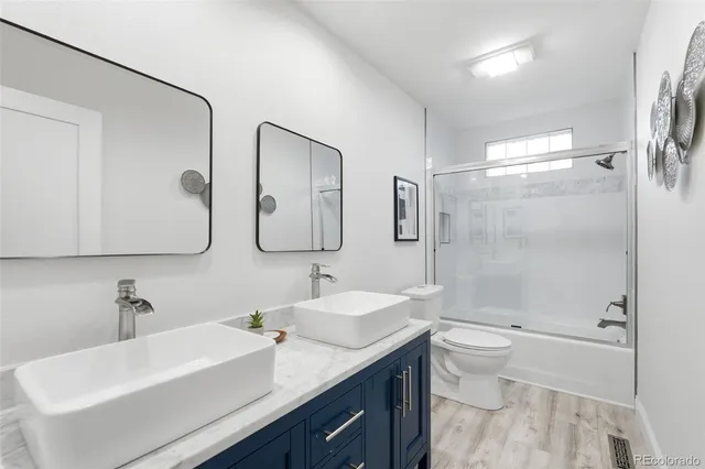 a bathroom with a double vanity sink toilet mirror and shower