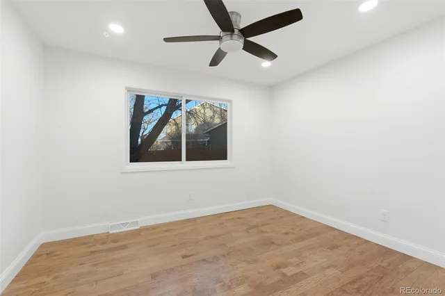 an empty room with a ceiling fan and window