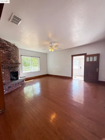 a view of a livingroom with wooden floor and a fireplace