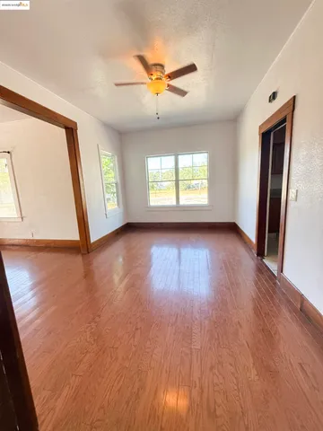 a view of a livingroom with wooden floor and a ceiling fan