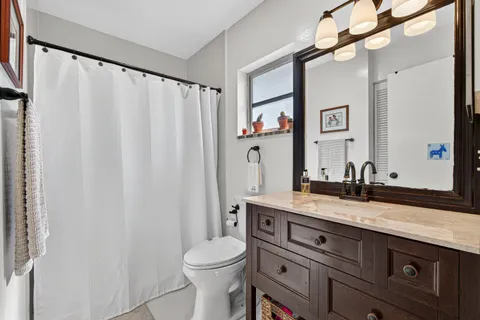 a bathroom with a granite countertop sink a toilet and a mirror