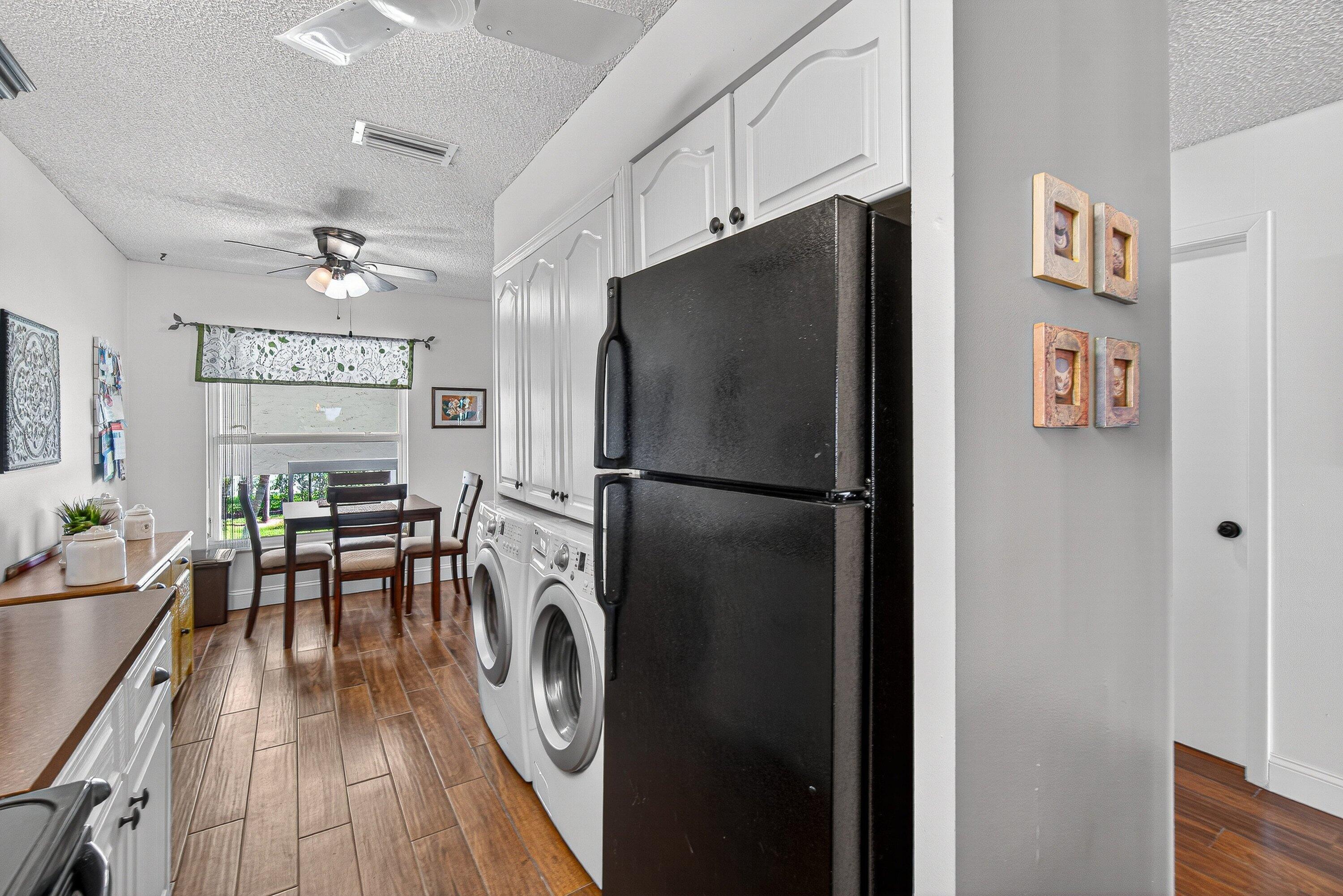 13465 Fishtail Palm Court, Unit D Delray Beach, FL 33484 - Photo 6 of 29 a kitchen with stainless steel appliances a refrigerator a stove a dining table and chairs with wooden floor