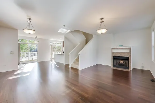 an empty room with wooden floor fireplace and windows