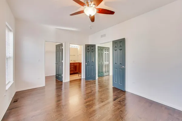 a view of an empty room with window a ceiling fan and wooden floor