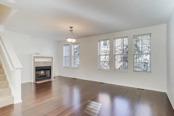 an empty room with wooden floor fireplace and windows