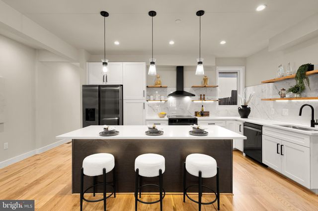 a kitchen with stainless steel appliances kitchen island a table and chairs in it