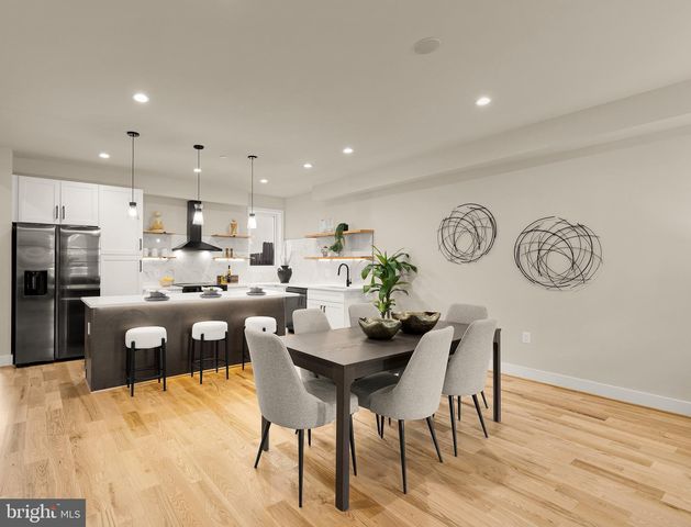 a living room with stainless steel appliances kitchen island granite countertop a table chairs and a refrigerator