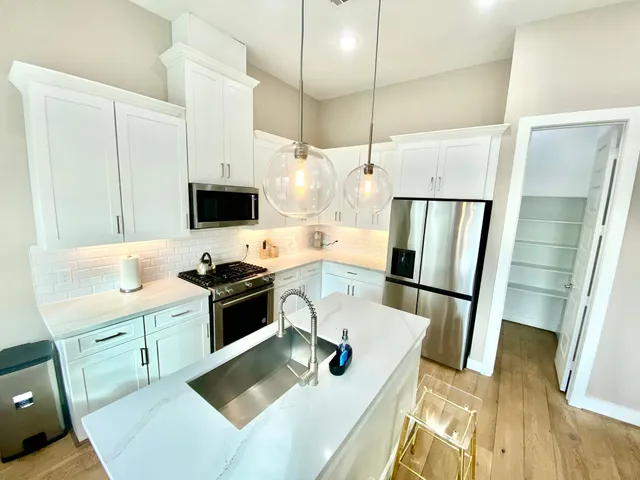 a view of a kitchen with a sink a microwave a refrigerator and wooden floor