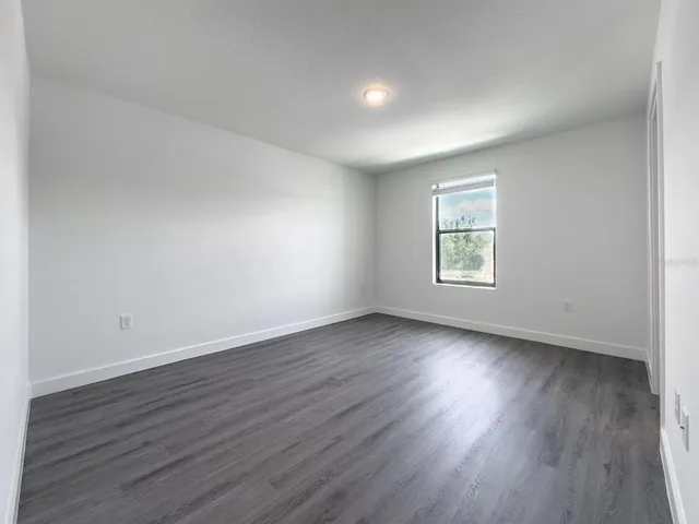 an empty room with wooden floor and window