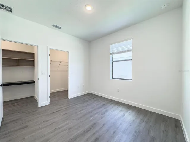 an empty room with wooden floor & closet area
