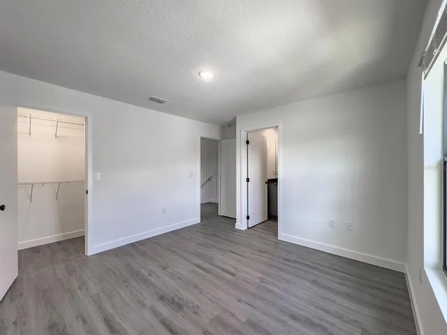 an empty room with wooden floor & windows and bathroom