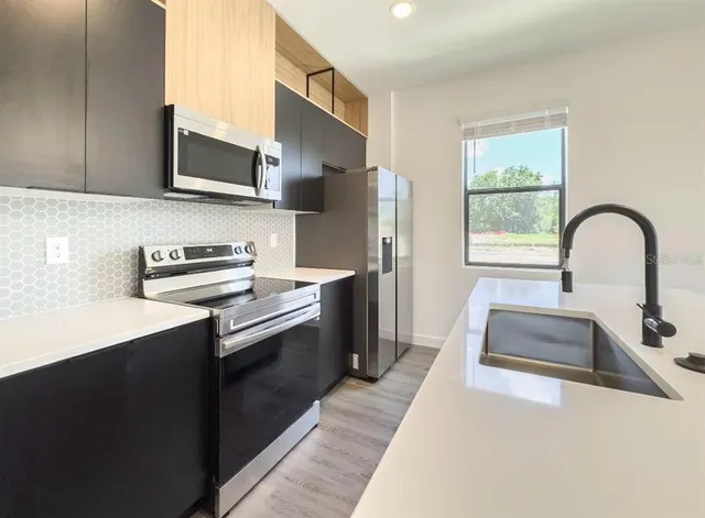 a kitchen with stainless steel appliances a sink a stove and a refrigerator with wooden floor