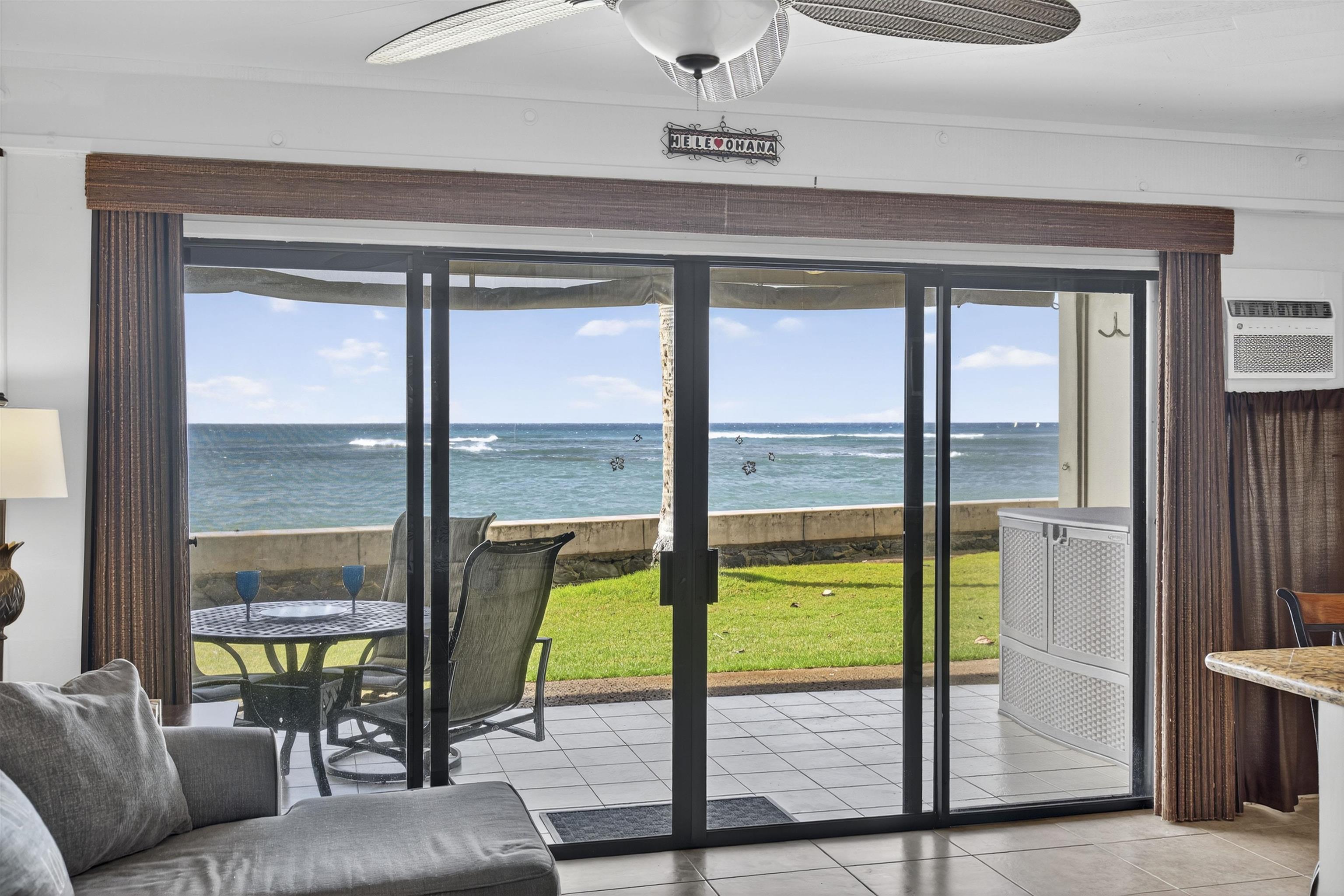 4435 Lower Honoapiilani Road, Unit 111 Lahaina, HI 96761 - Photo 24 of 50 a living room with a floor to ceiling window and a table
