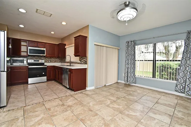 a large kitchen with kitchen island granite countertop a stove top oven a sink a counter space and cabinets