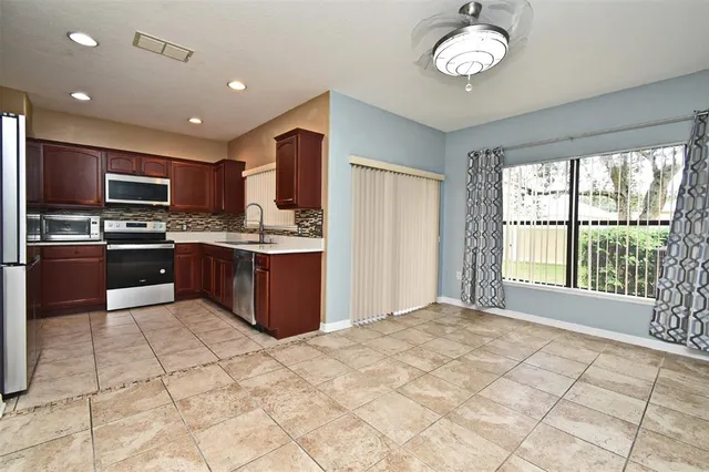 a large kitchen with kitchen island granite countertop a stove top oven a sink a counter space and cabinets