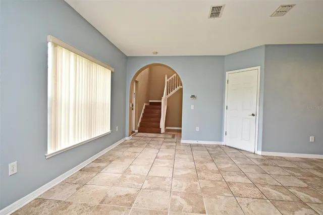 a view of an empty room with window and a kitchen