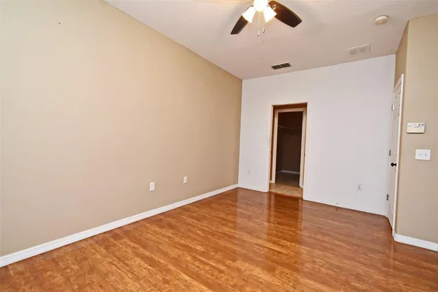 an empty room with ceiling fan and wooden floor