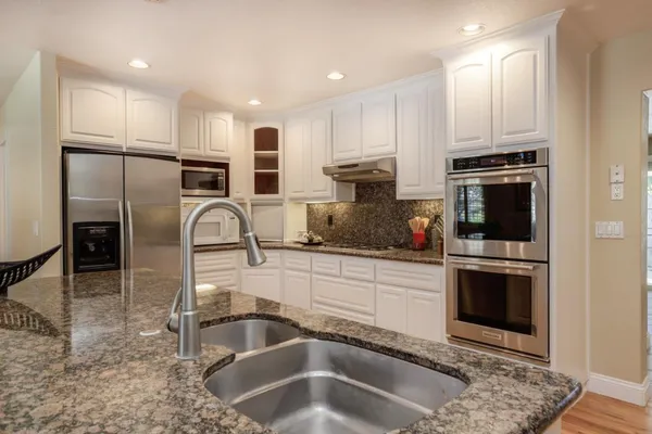 a kitchen with stainless steel appliances granite countertop a sink a stove and a refrigerator