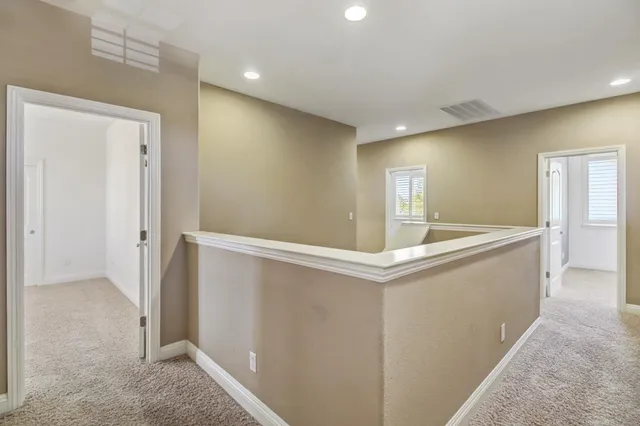 an empty room with a chandelier fan and windows
