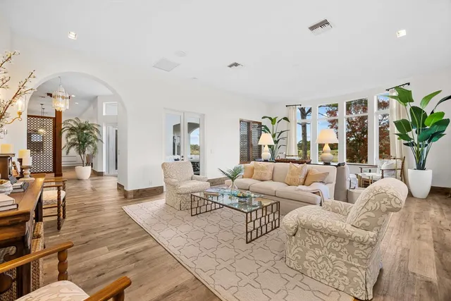 a large white kitchen with wooden floor and a chandelier